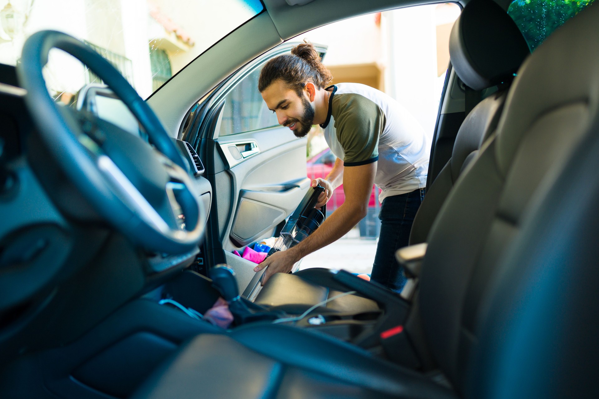 Happy man vacuuming the car seats